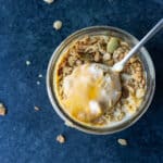 a spoon dipped into a vegan pumpkin swirl yogurt parfait topped with granola