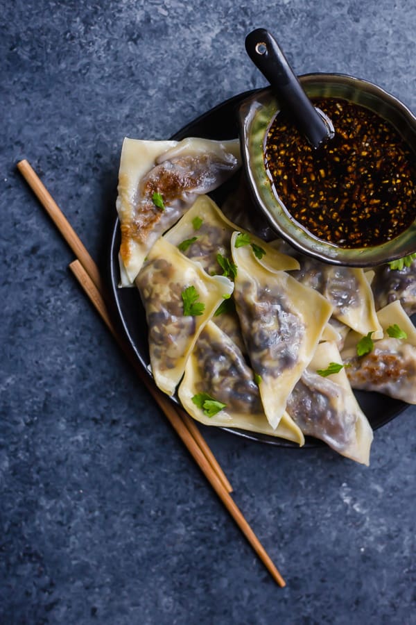 vegetable potstickers on a plate with chopsticks and dipping sauce
